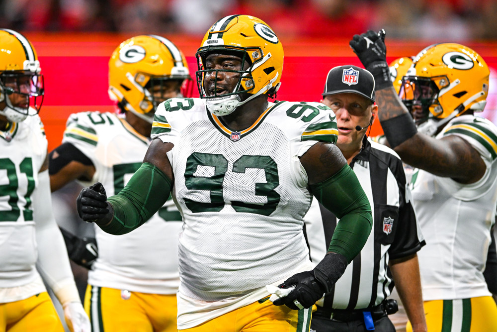 T.J. Slaton, wearing a yellow helmet, white jersey, and green number 93 on his jersey, receives congratulations from his teammates