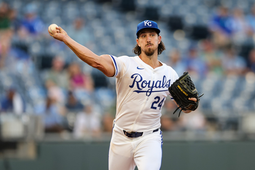 Royals pitcher Michael Lorenzen- in a white shirt and blue cap with blue lettering on the shirt- makes a throw to first base.