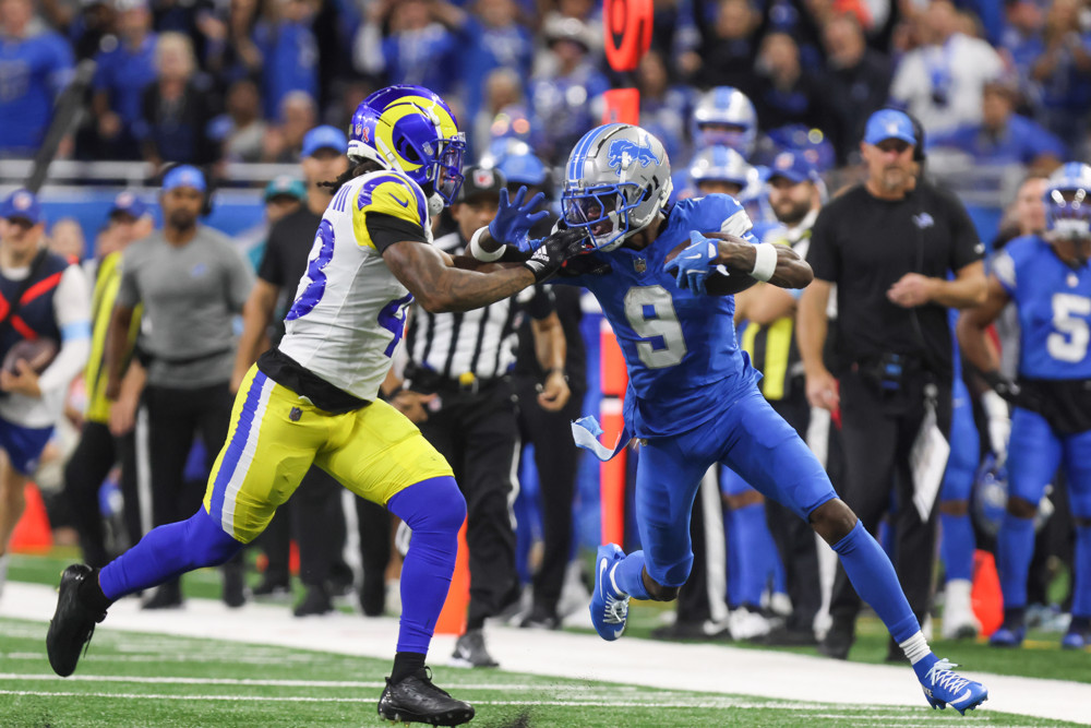 Jameson Williams (9) runs with the ball after catching a pass while evading Los Angeles Rams safety John Johnson