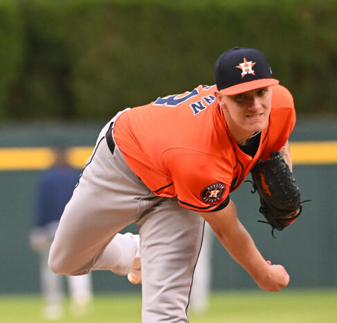 Hunter Brown - wearing an orange jersey and grey pants- delivers a pitch