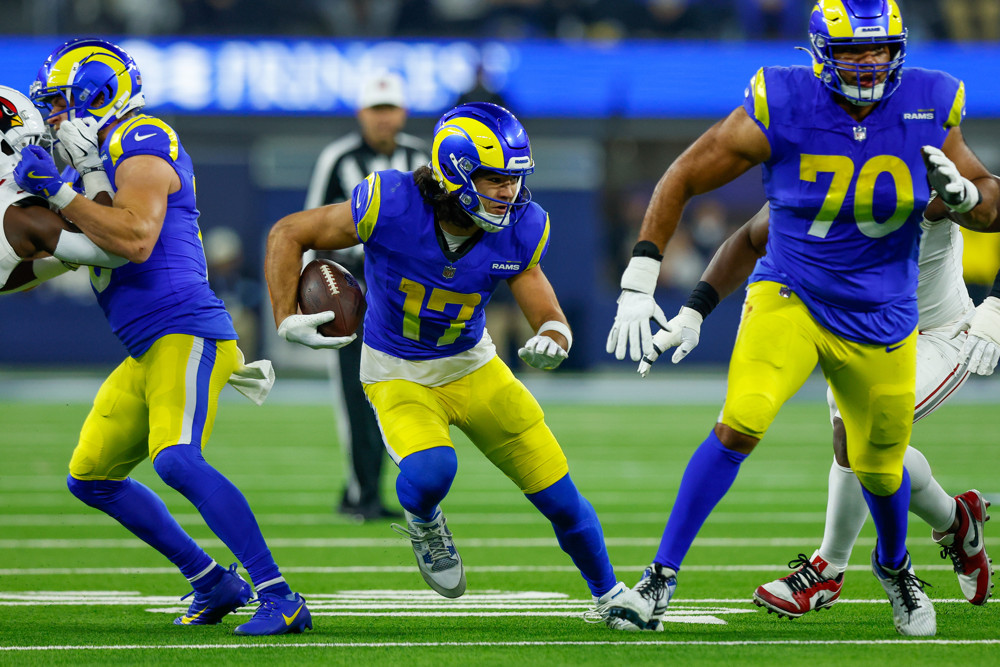 Puka Nacua, dressed in yellow pants, blue jersey, and blue high socks, with a yellow and blue helmet, runs upfield for the Rams.