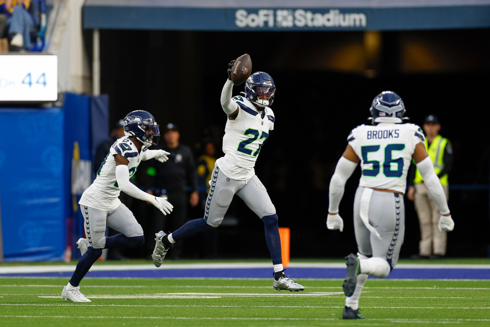 Riq Woolen celebrates an interception just outside the end zone by raising the football with his right hand