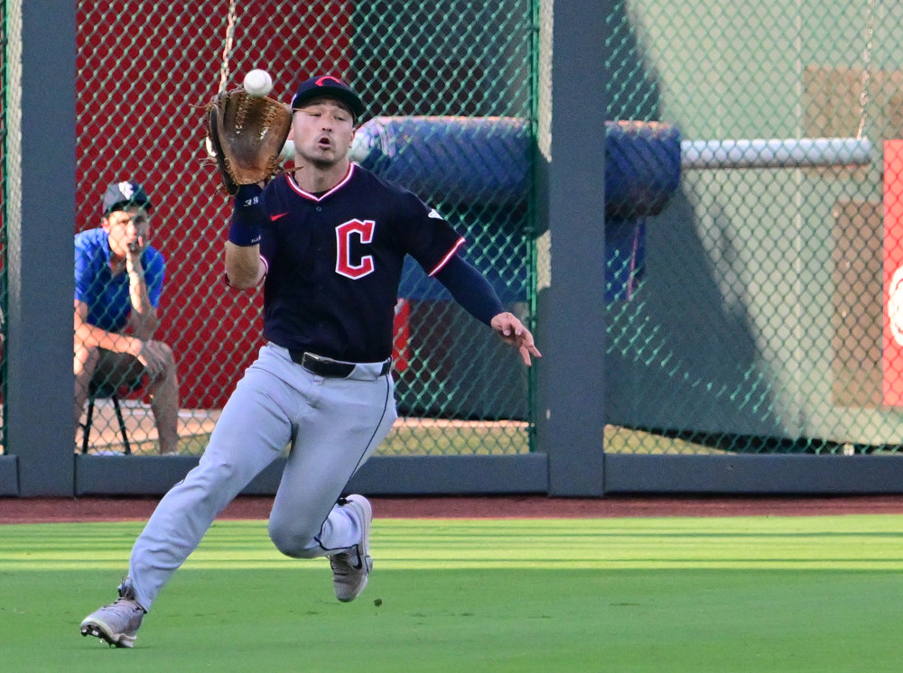 Steven Kwan is about to catch a fly ball hit towards the left field line.