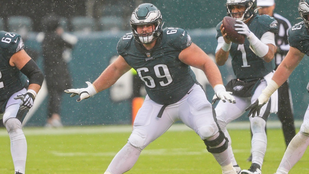 Landon Dickerson, in green jersey with #69 and white pants holds his arms out, palms down, as he prepares to block.