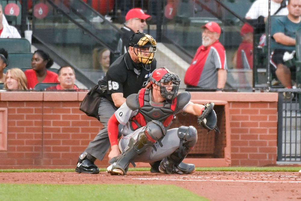 Tyler Stephenson catches a pitch as the home plate umpire is hunched over him, ready to call strike 3.